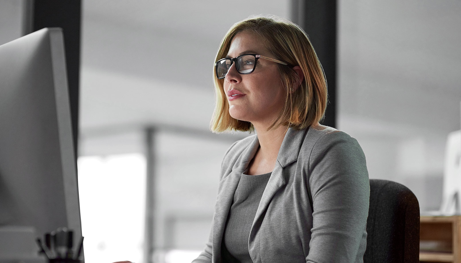 woman with glasses looking at computer