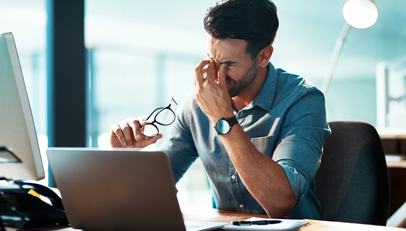 Man at desk with eye strain headache